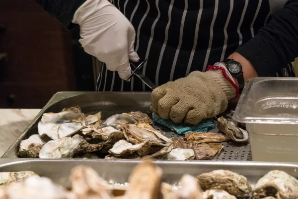 Man wearing gloves prepping oysters to cook